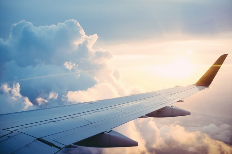 Airplane wing over clouds at sunset symbolizing AI in corporate travel